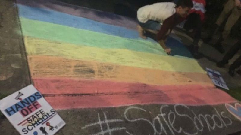 Person chalking Rainbow flag on footpath