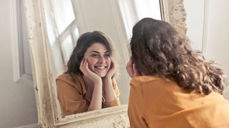 woman looking into mirror smiling