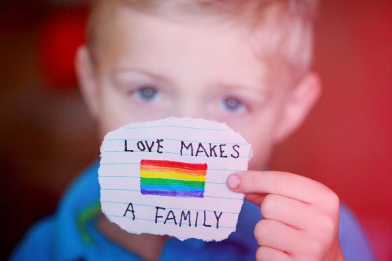 Child holding a note: love makes a family