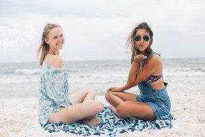2 young women sitting on a beach