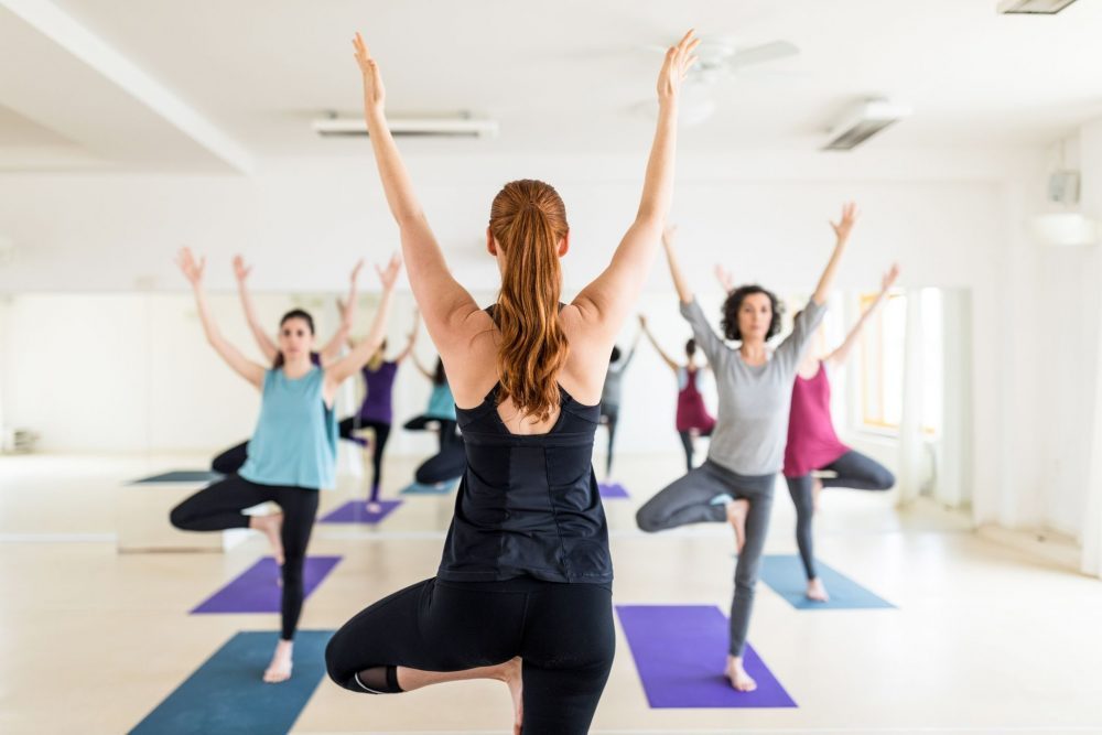 female-instructor-with-yoga-class-in-the-gym