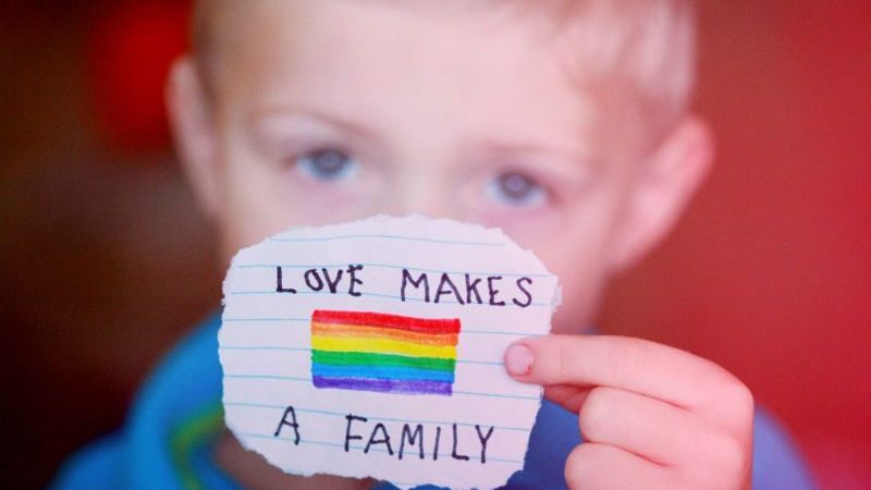 Child holding a note: love makes a family