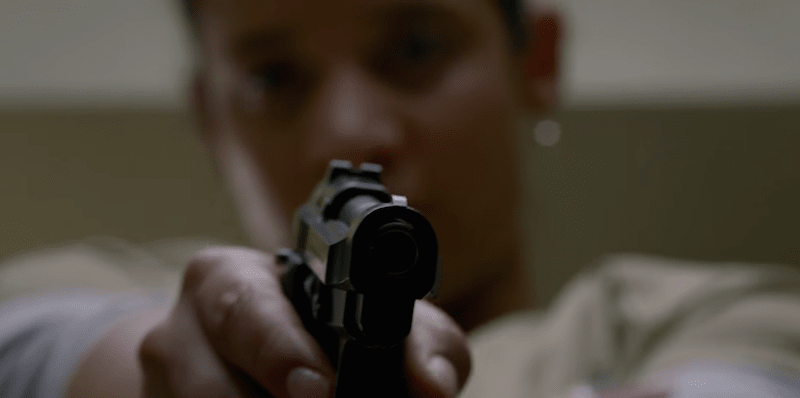 Daya (Dascha Polanco) aiming a gun at corrections officer Thomas Humphrey (Michael Torpey). 
