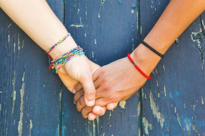 2 women with braclets holding hands