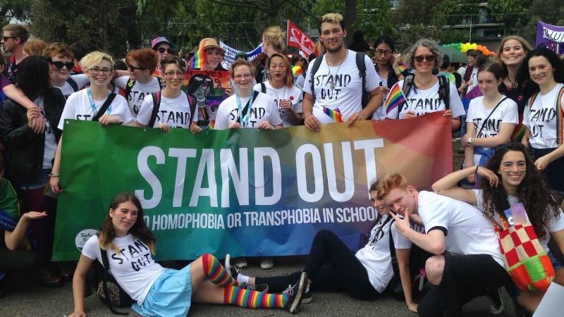 demostrators stand behind stand out banner