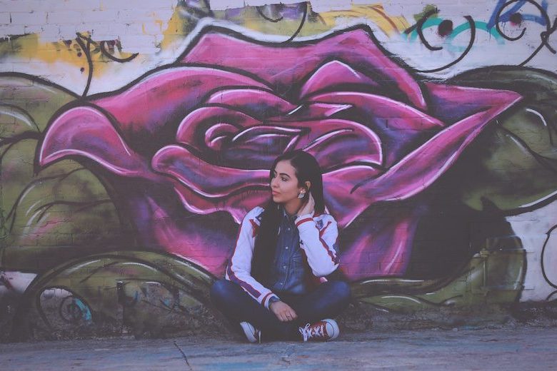 woman sitting in front of graffity wall