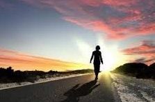 woman walking into sunset on a road